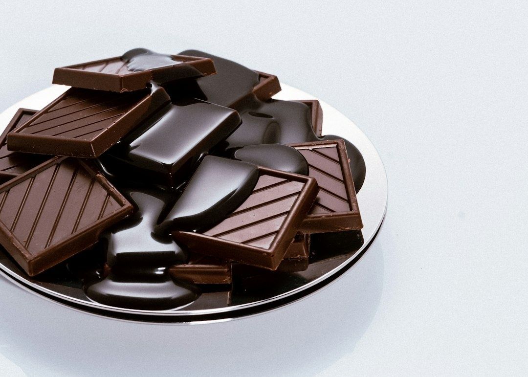 Dark and milk chocolate pieces piled over glossy melted chocolate